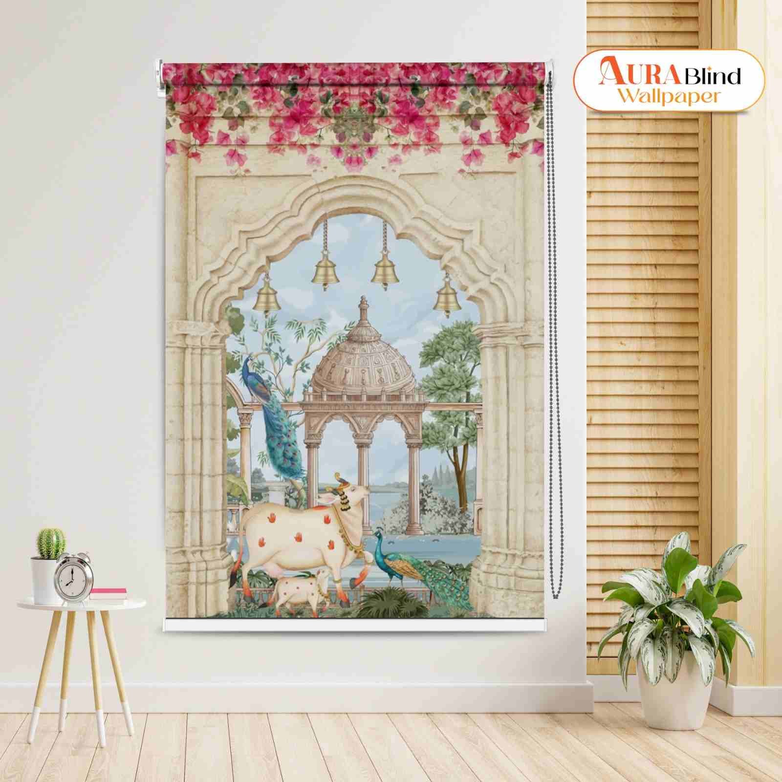 This Divine Kamadhenu Cow Design Pichwai Temple Roller Blind featuring an intricate Indian art scene of a white Kamadhenu cow and calf with two peacocks beneath a stone archway, showing a domed temple pavilion and water in the background, topped with a border of pink flowers and brass bell motifs.